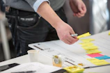 Close-up of hands arranging colorful sticky notes on a wall, illustrating planning and workflow.