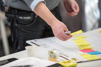 person holding yellow and white pen writing on white paper