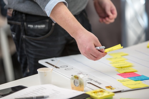 person holding yellow and white pen writing on white paper