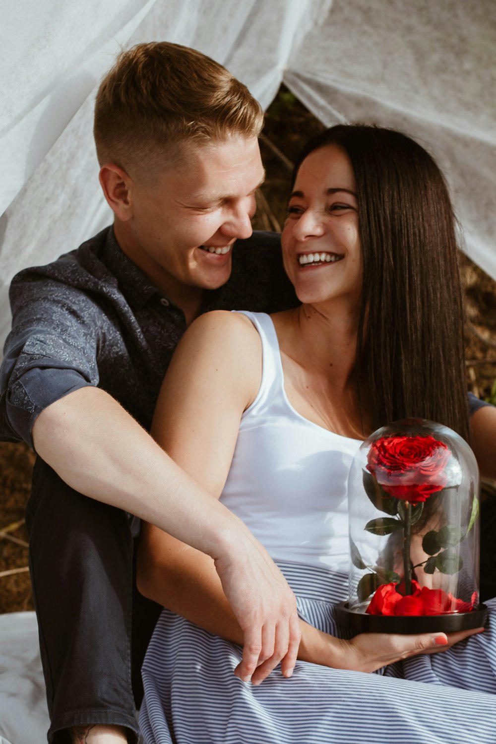 man in gray sweater kissing woman in white tank top