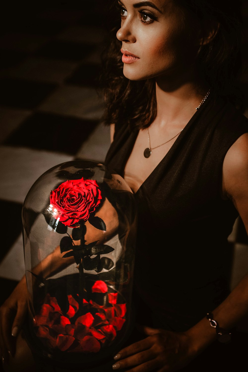 woman in black tank top holding red rose