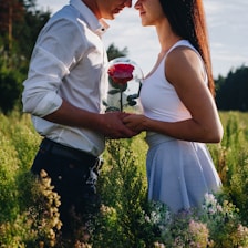 man in white dress shirt holding red rose