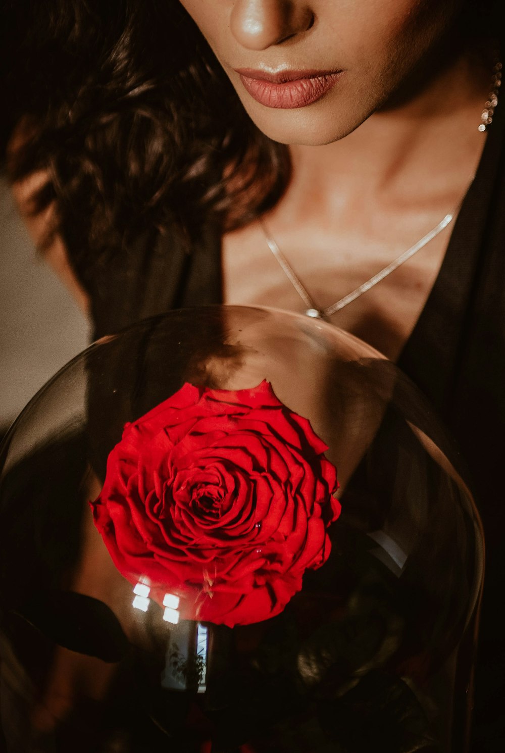 woman in black scoop neck shirt holding red rose