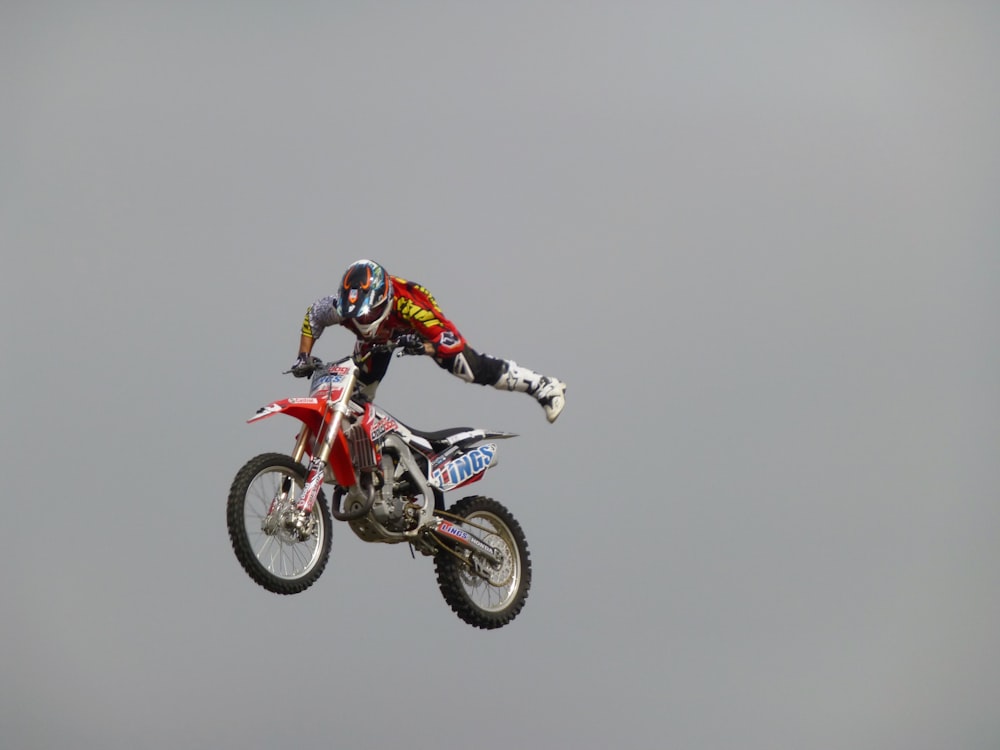 Homme en costume de motocross rouge et blanc chevauchant une moto tout-terrain de motocross