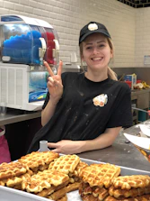 Friendly staff member serving a customer with a warm smile at the counter.