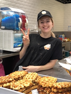 A smiling staff member serving food at the counter.