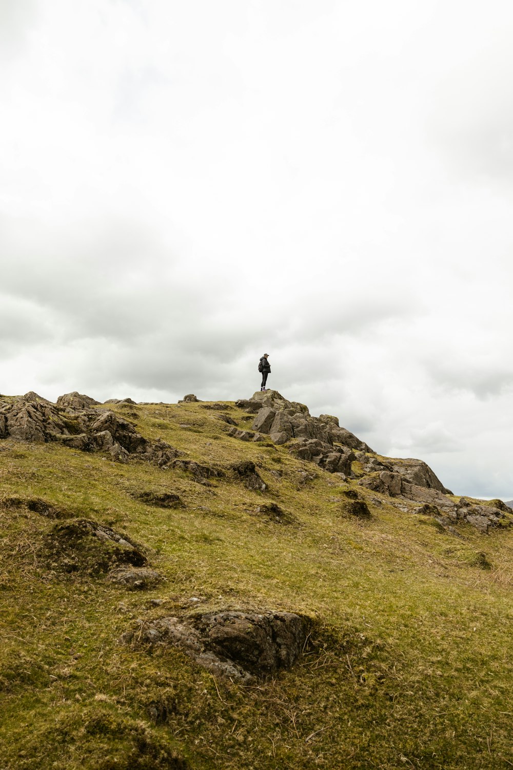 person standing on rock formation under white sky during daytime