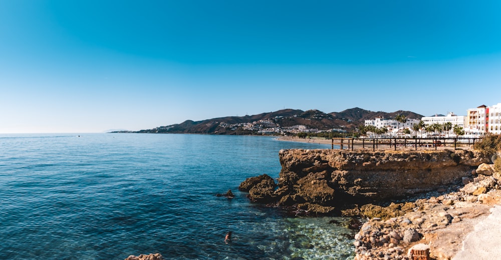 people standing on brown rock formation near sea during daytime