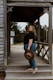 woman in black t-shirt and blue denim jeans holding brown hat