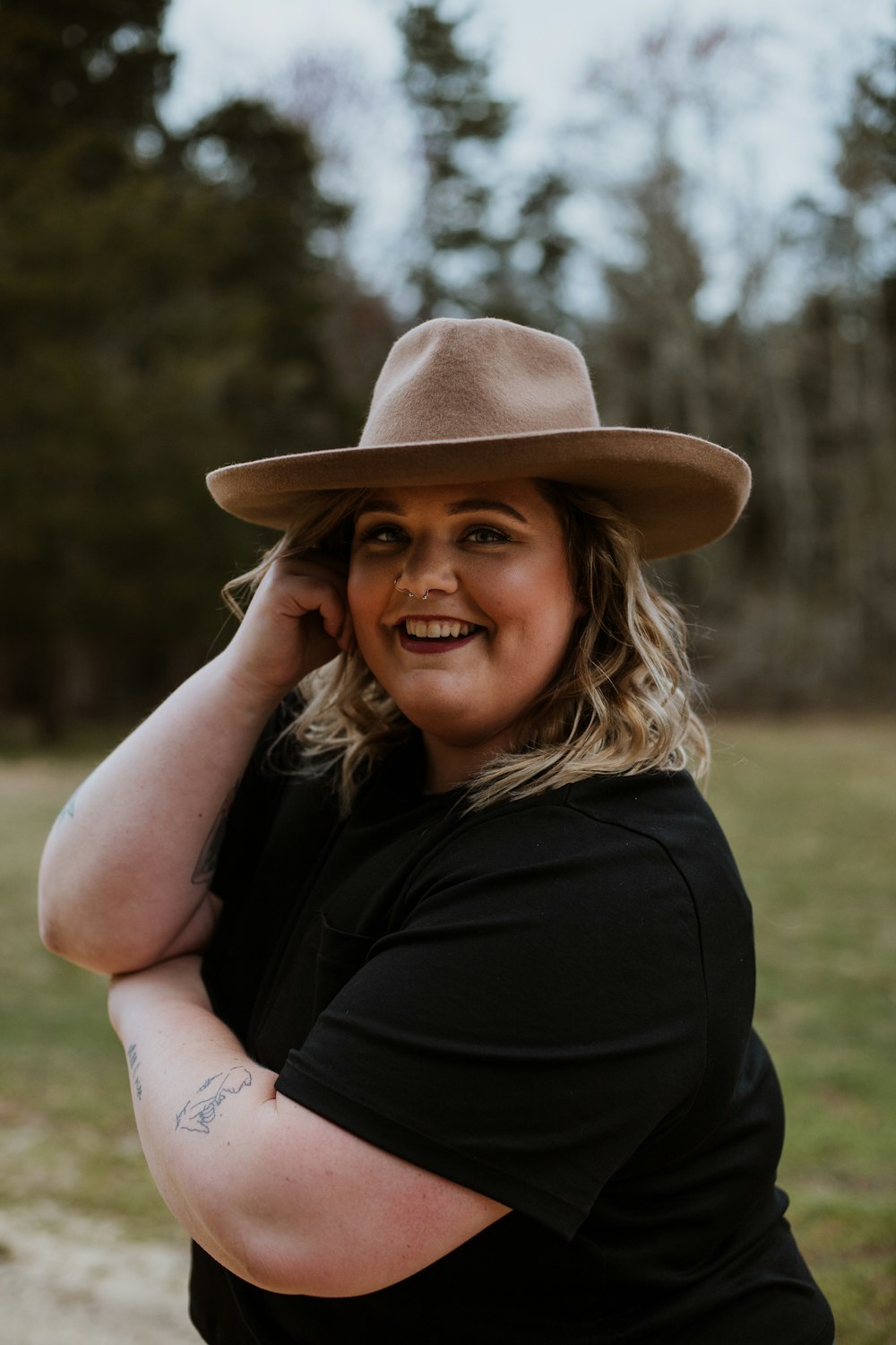 woman in black sleeveless dress wearing brown fedora hat