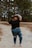 woman in black t-shirt and blue denim jeans standing on dirt road during daytime