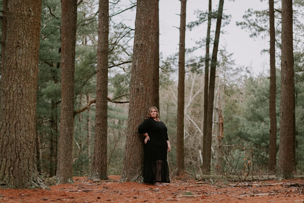 昼間、森の中に立つ黒いコートの女性