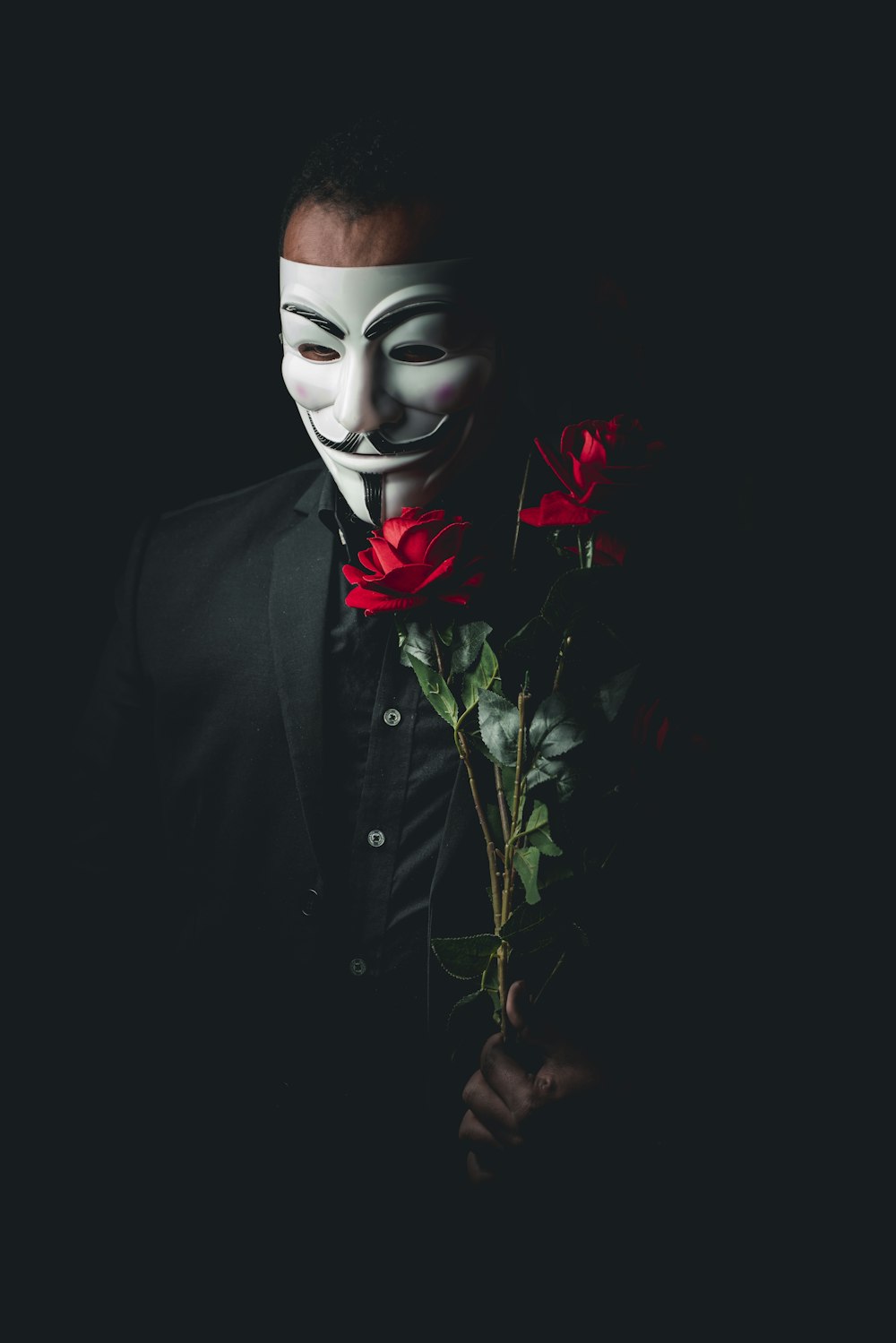 person in black suit with red rose on face