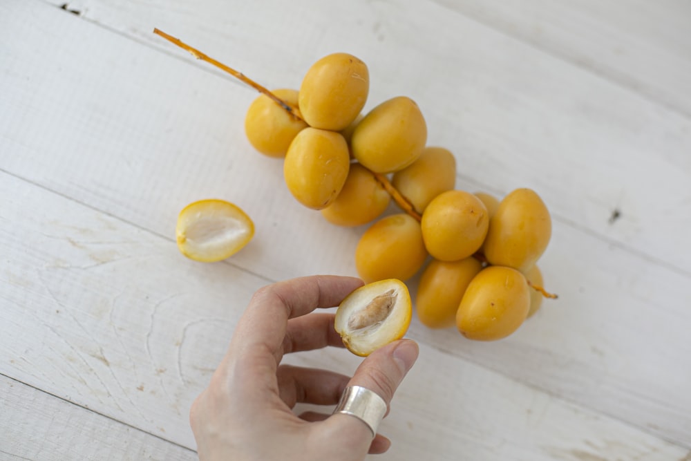 person holding yellow round fruits