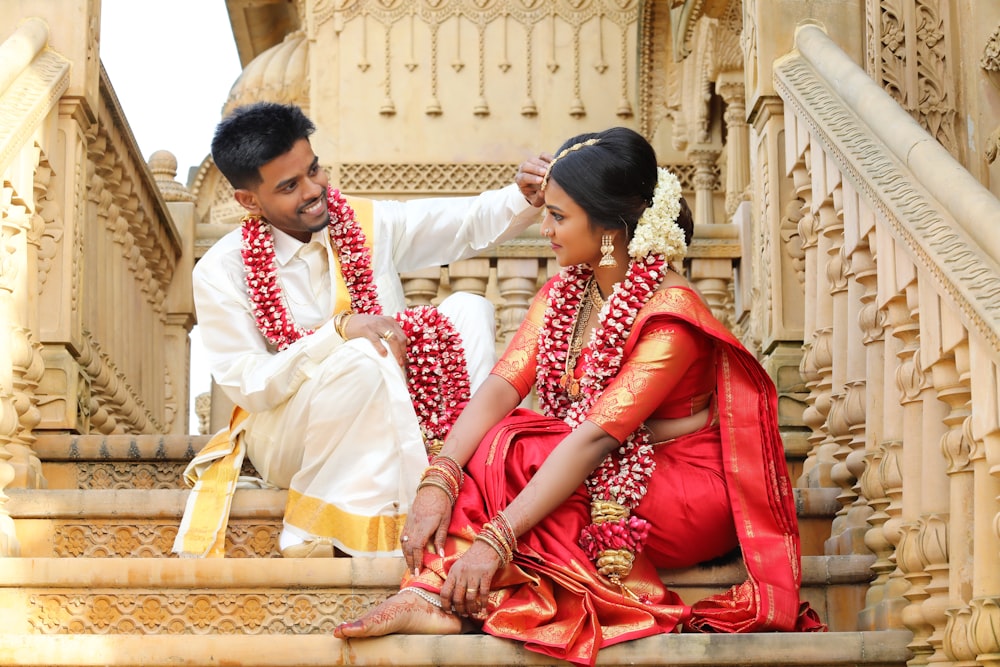 man in red thobe sitting beside woman in white long sleeve shirt