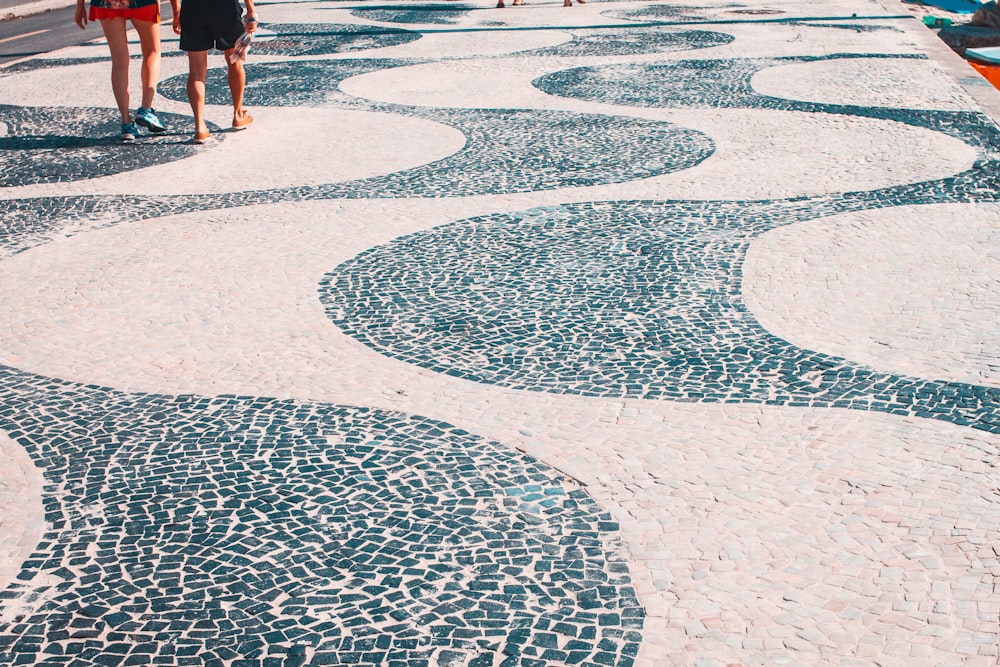 2 donne che camminano sul pavimento rotondo di cemento bianco e blu durante il giorno