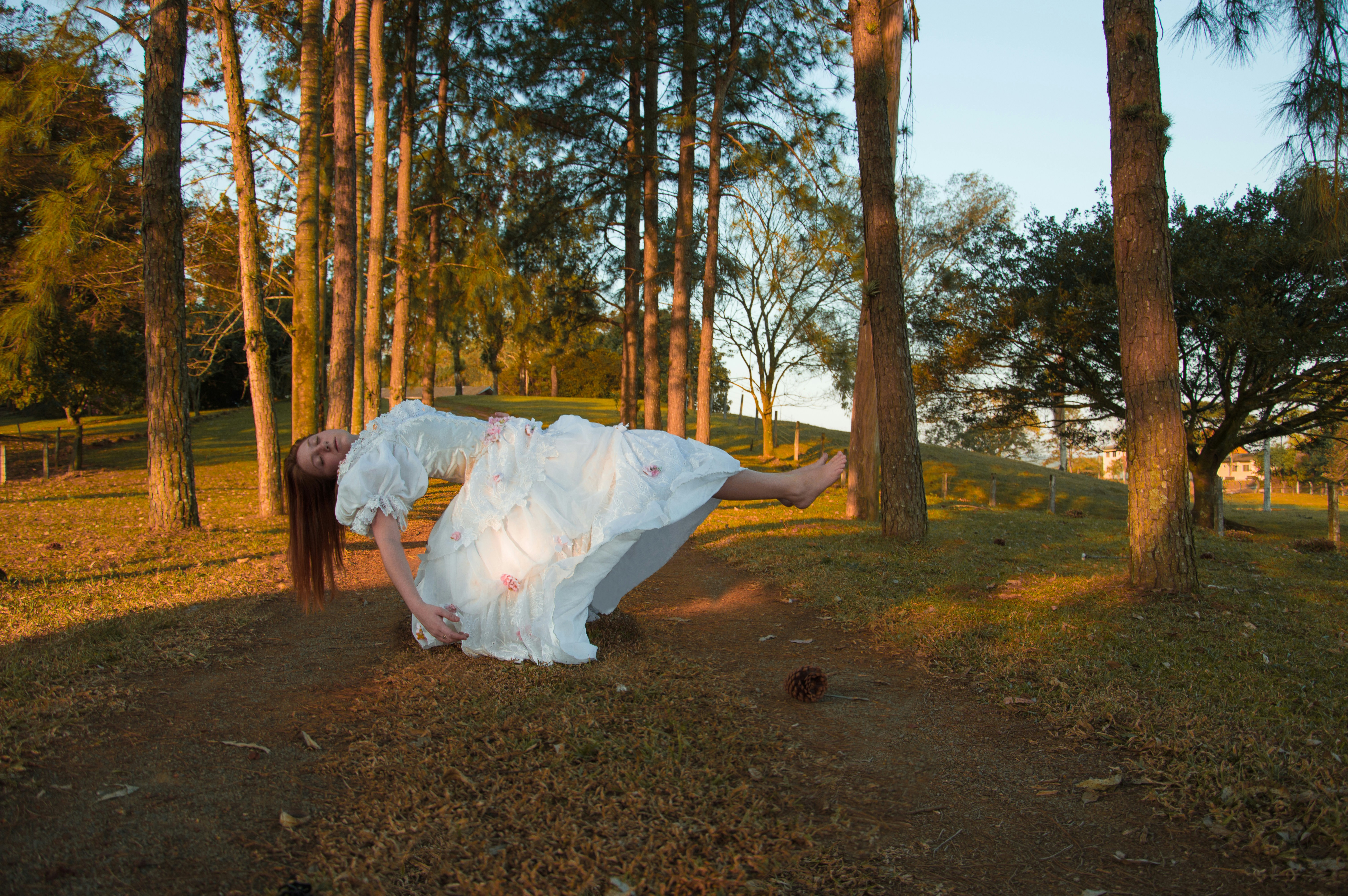 mulher no vestido branco que anda na estrada de terra marrom durante o dia