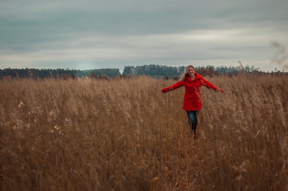 woman in red jacket standing on brown grass field during daytime
