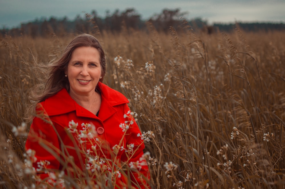 woman in red coat standing on brown grass field during daytime