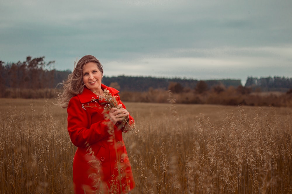 woman in red long sleeve dress standing on brown grass field during daytime