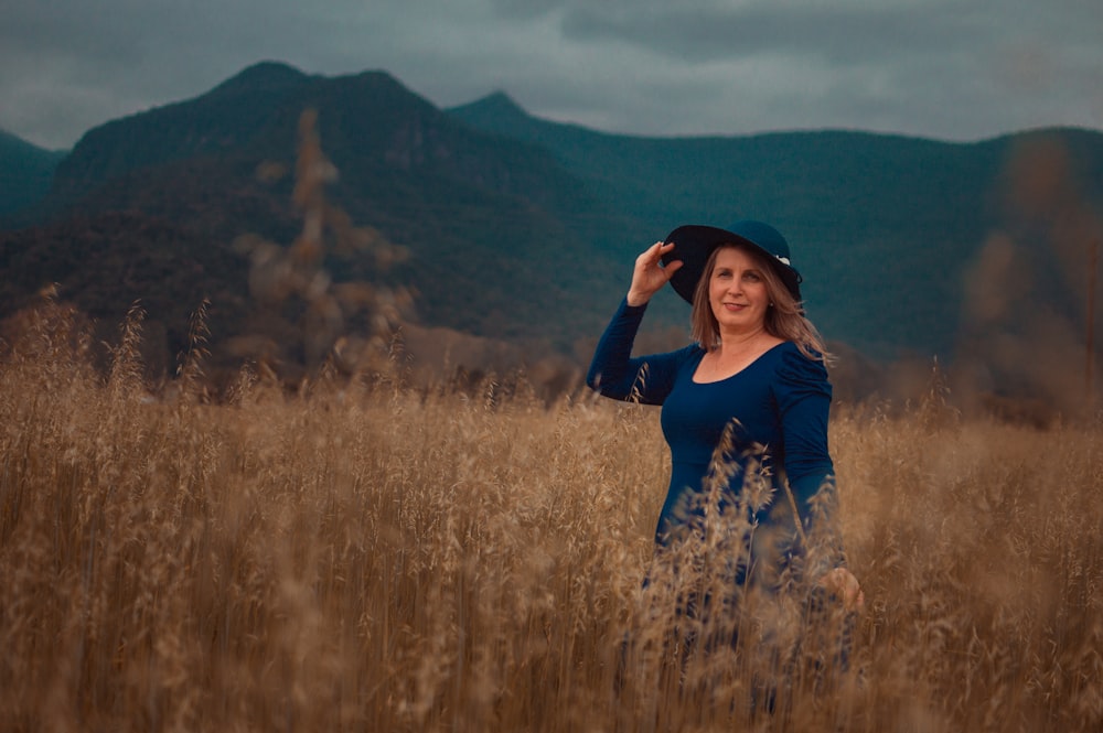 woman in blue long sleeve shirt standing on brown grass field during daytime