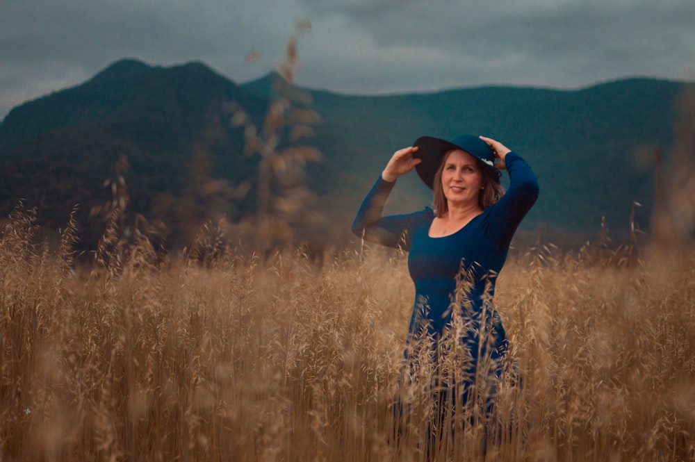 woman in blue shirt standing on brown grass field during daytime