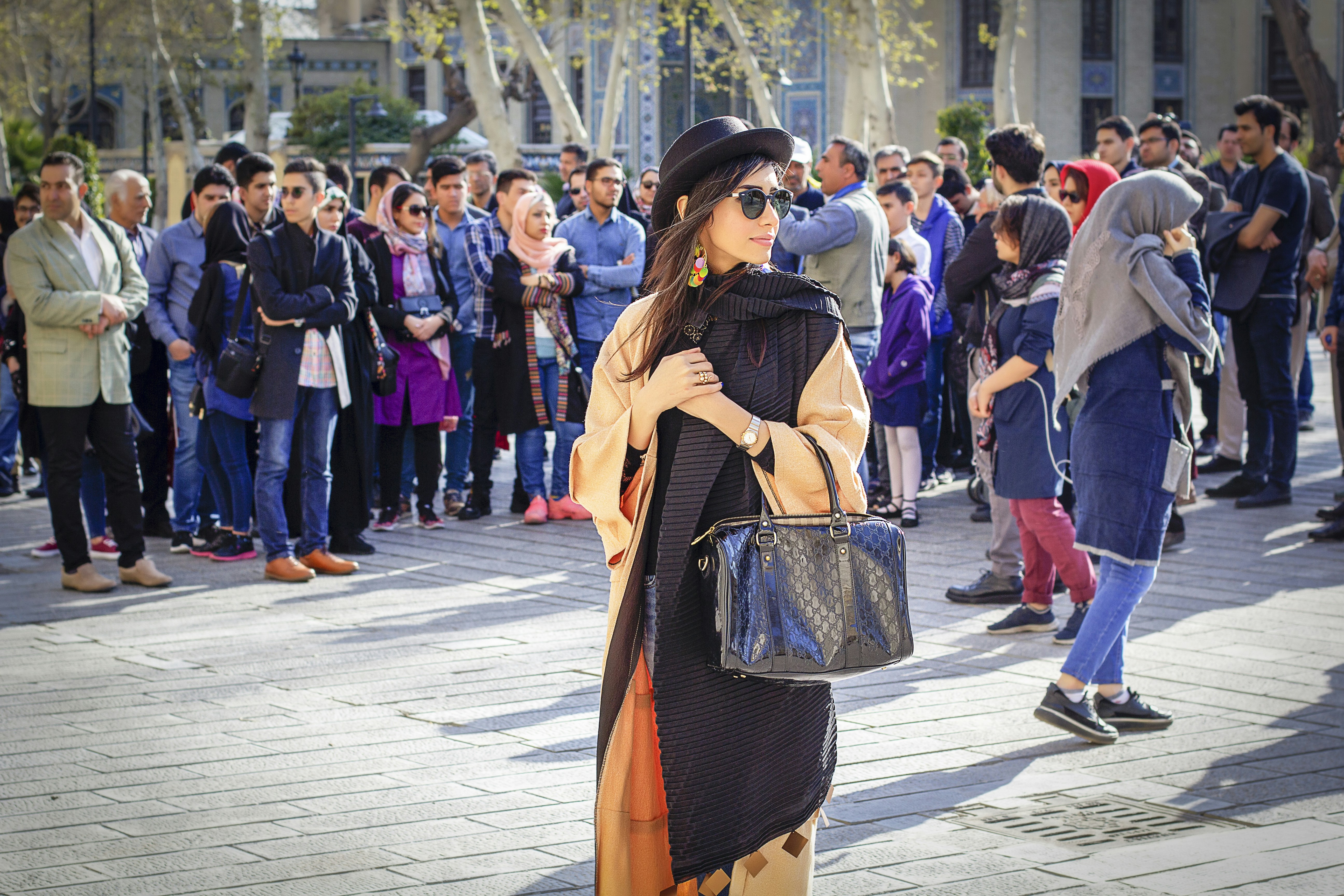 woman in black hat and brown coat walking on street during daytime