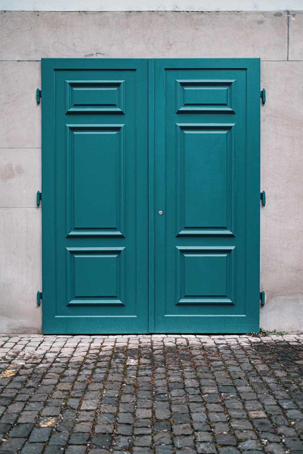 porta in legno blu su pavimento in mattoni grigi