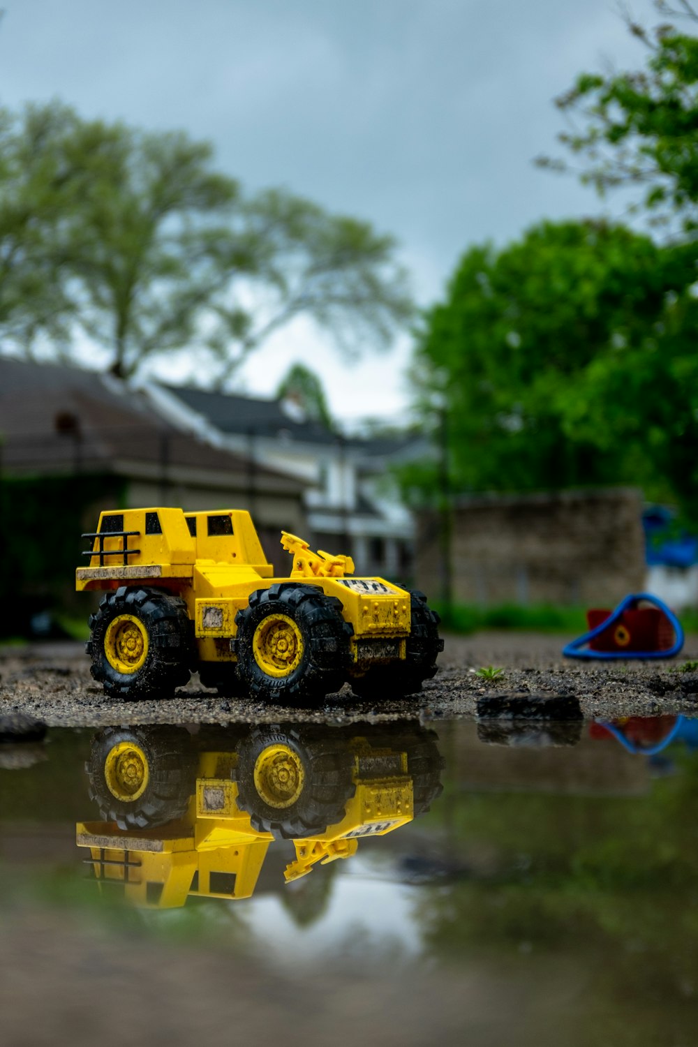 Ein gelber Spielzeuglastwagen, der auf einer Wasserpfütze sitzt