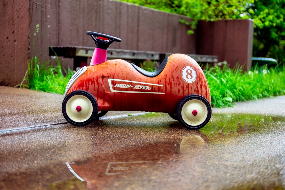 red and black ride on toy car on gray concrete floor