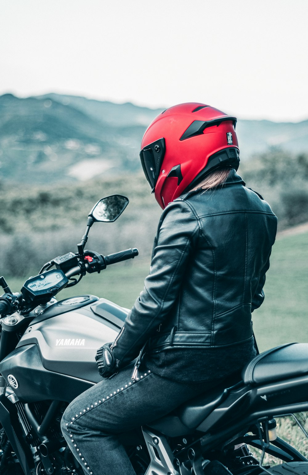검은 가죽 재킷을 입은 남자 빨간 헬멧을 타고 검은 혼다 오토바이