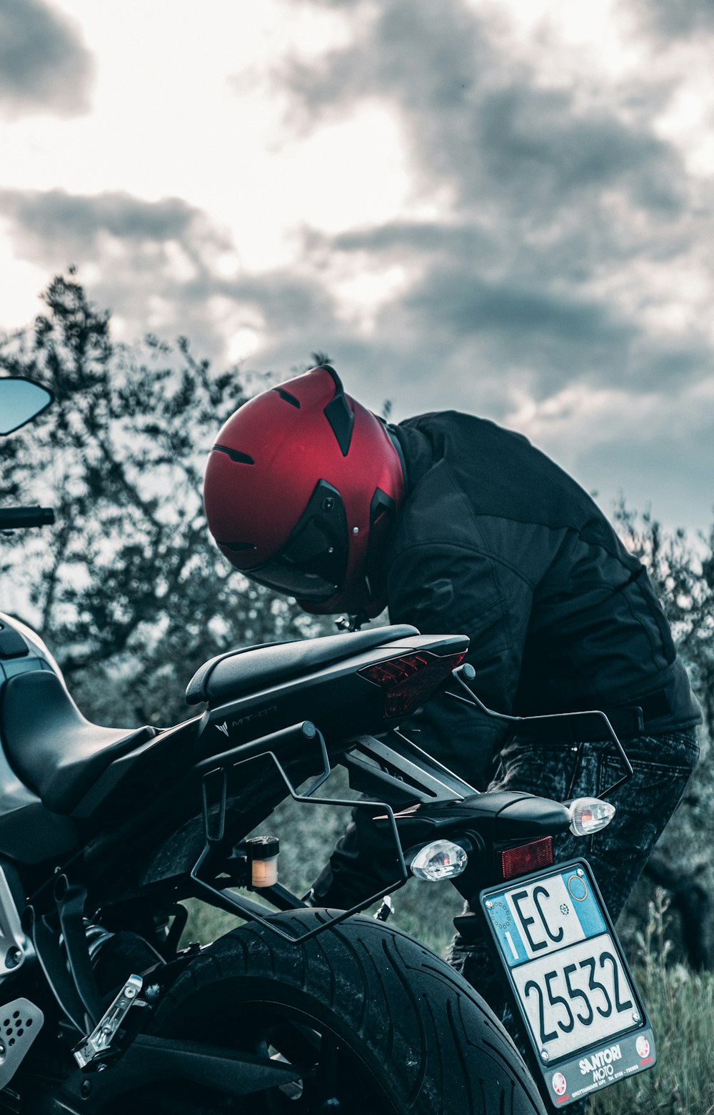 homme en veste noire et casque rouge conduisant une moto