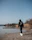 man in black hoodie standing on brown field near lake during daytime