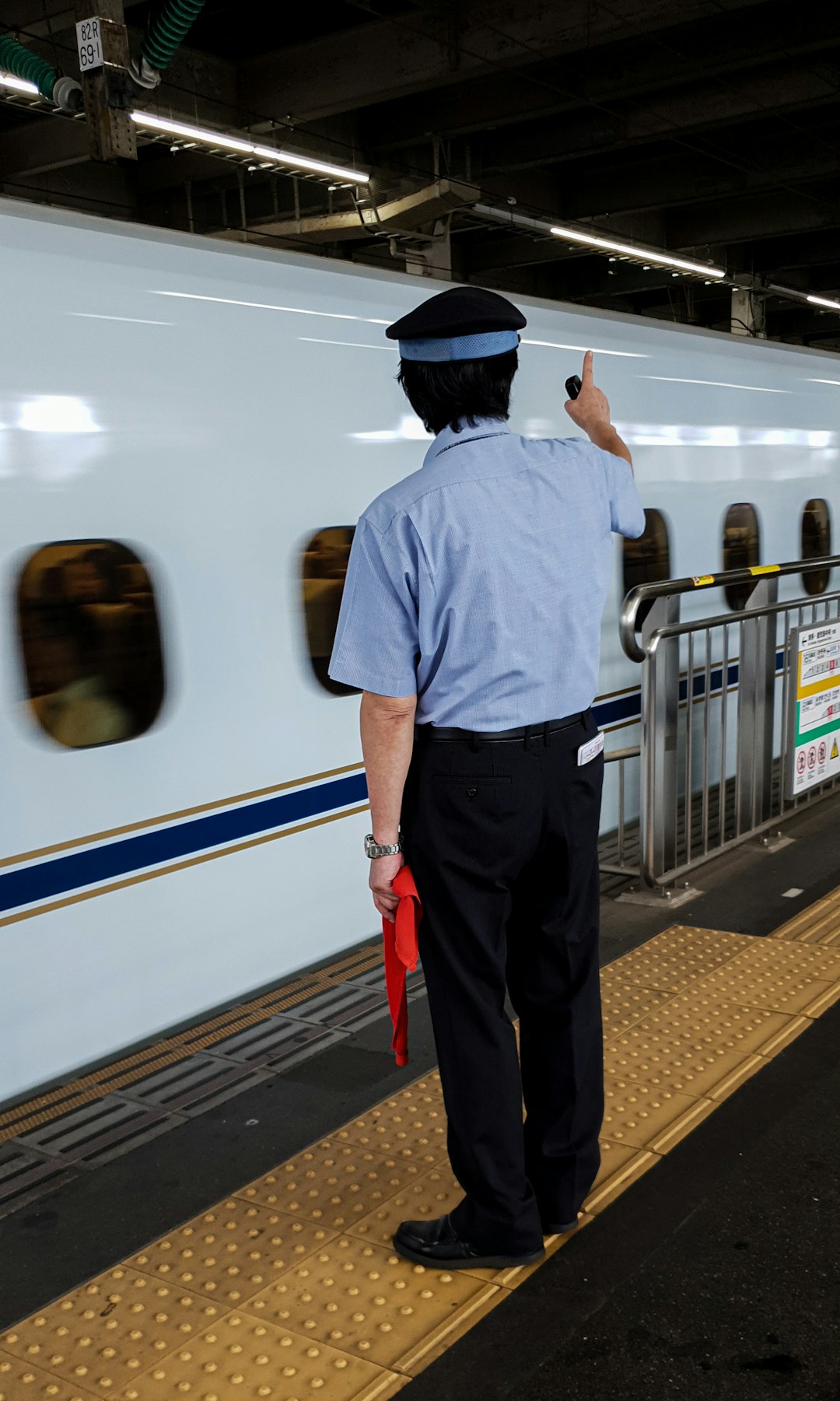 man in white dress shirt and black pants standing beside white and blue train