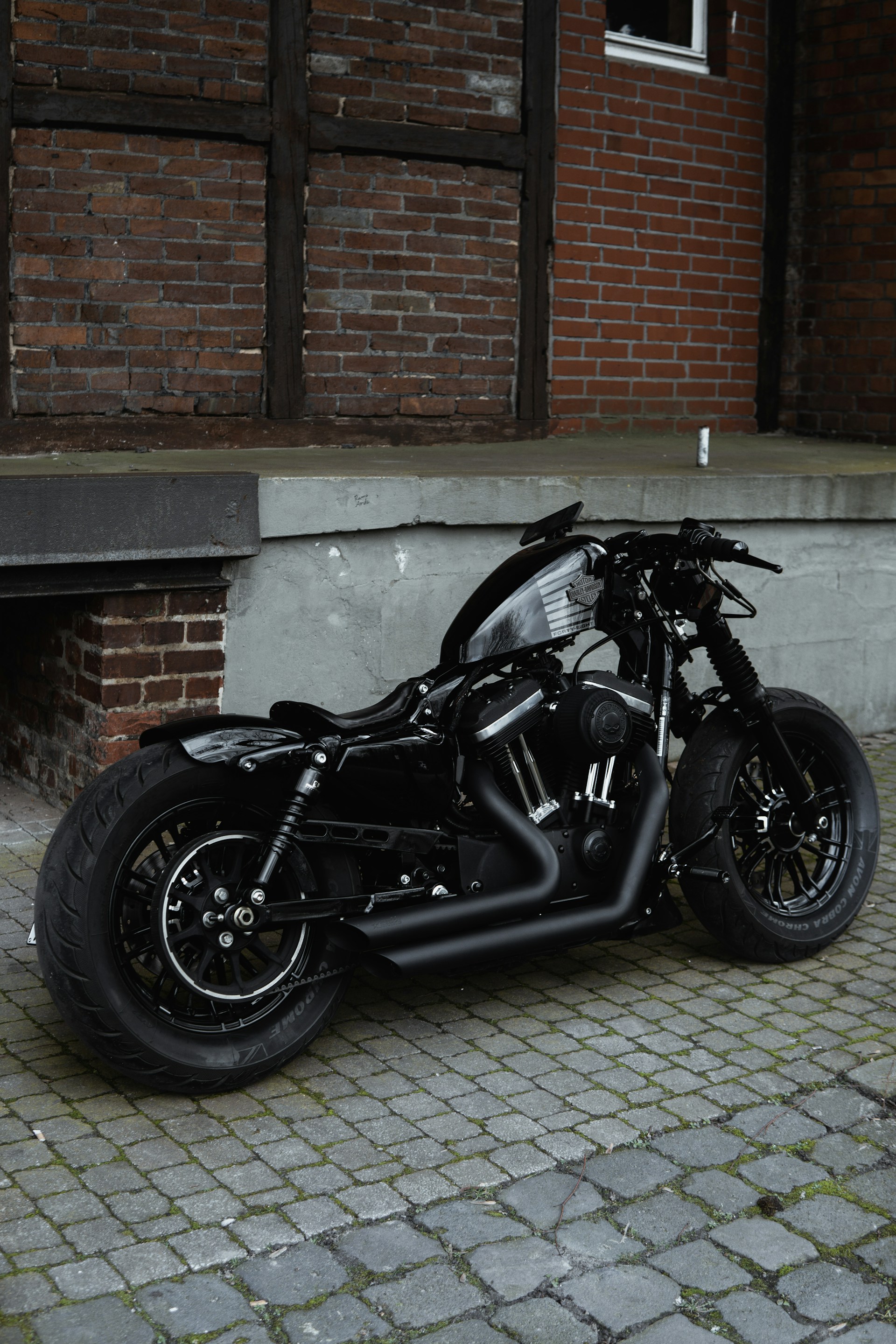 black motorcycle parked beside brown brick wall