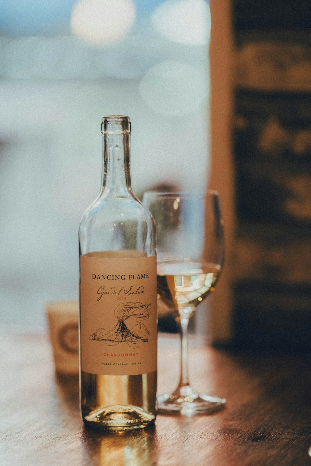 white labeled bottle beside clear wine glass on table