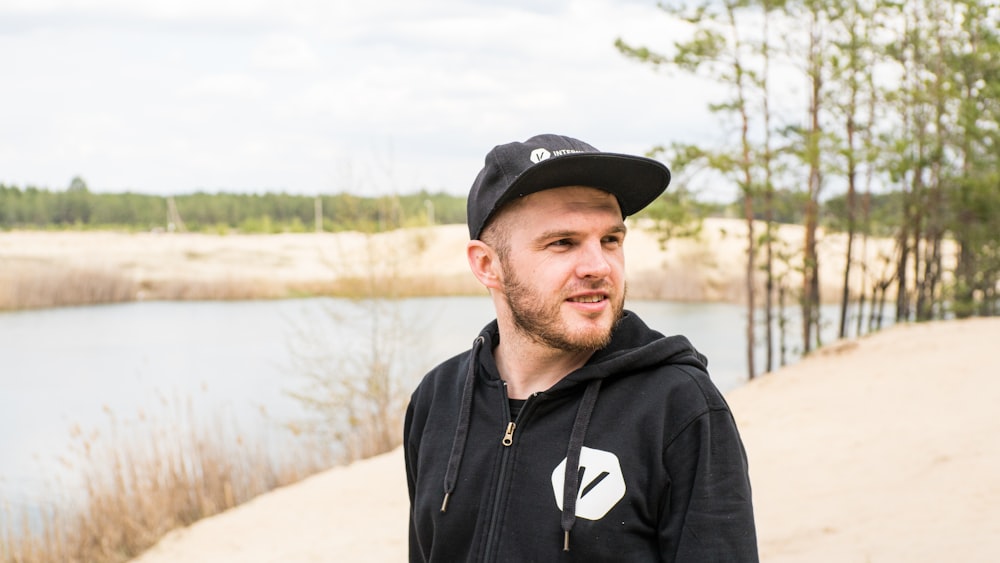 man in black nike zip up hoodie standing near lake during daytime