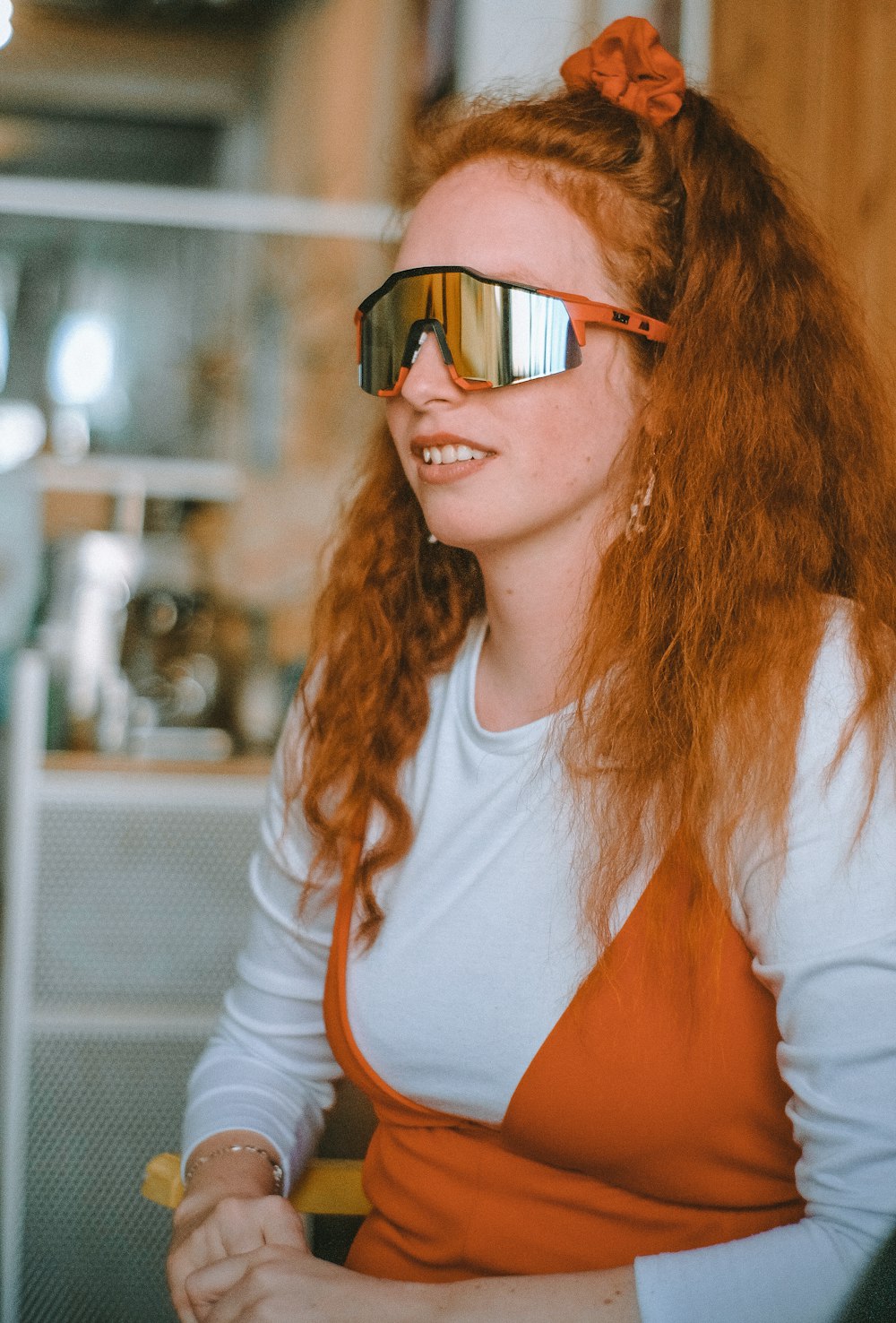 Frau in weiß-orangefarbenem Langarmhemd mit schwarz gerahmter Brille