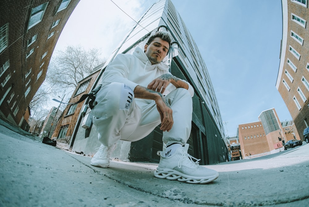 man in white shirt and pants sitting on gray concrete floor