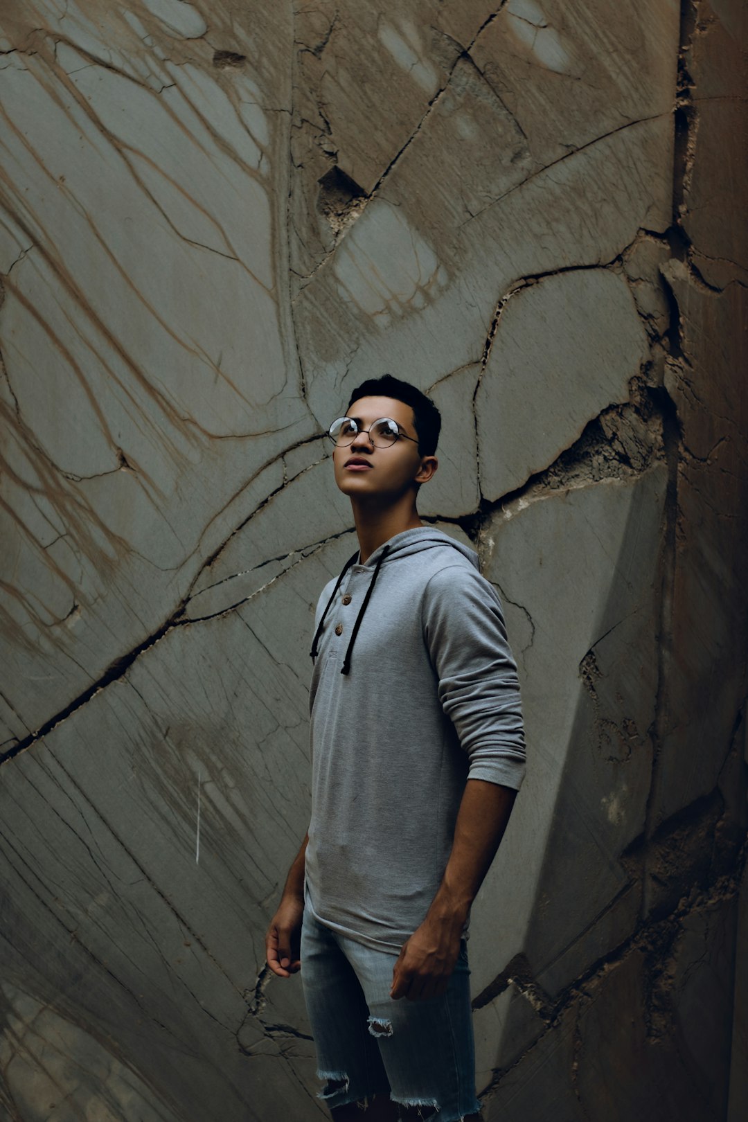 man in gray crew neck t-shirt and black sunglasses standing beside wall