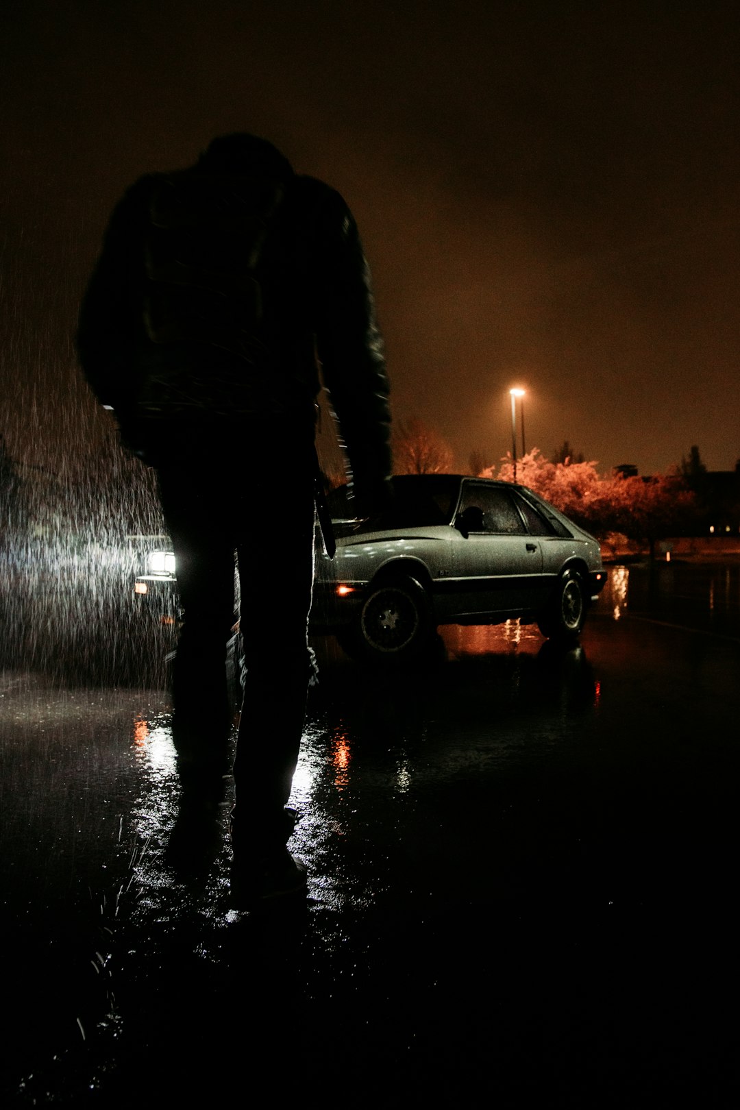 man in black jacket standing on road during night time