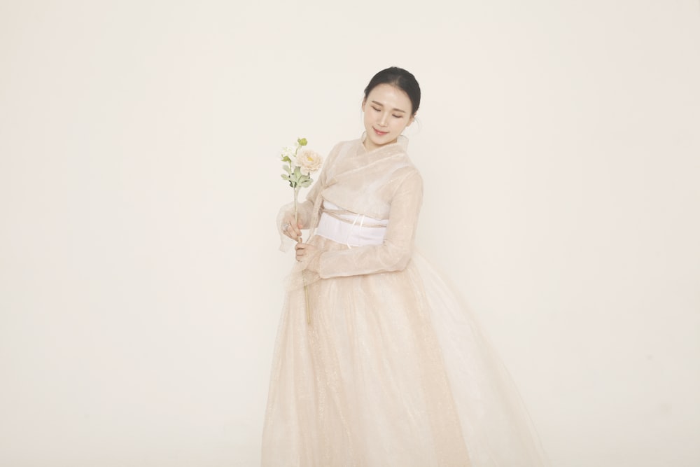 mujer en vestido blanco sosteniendo ramo de flores