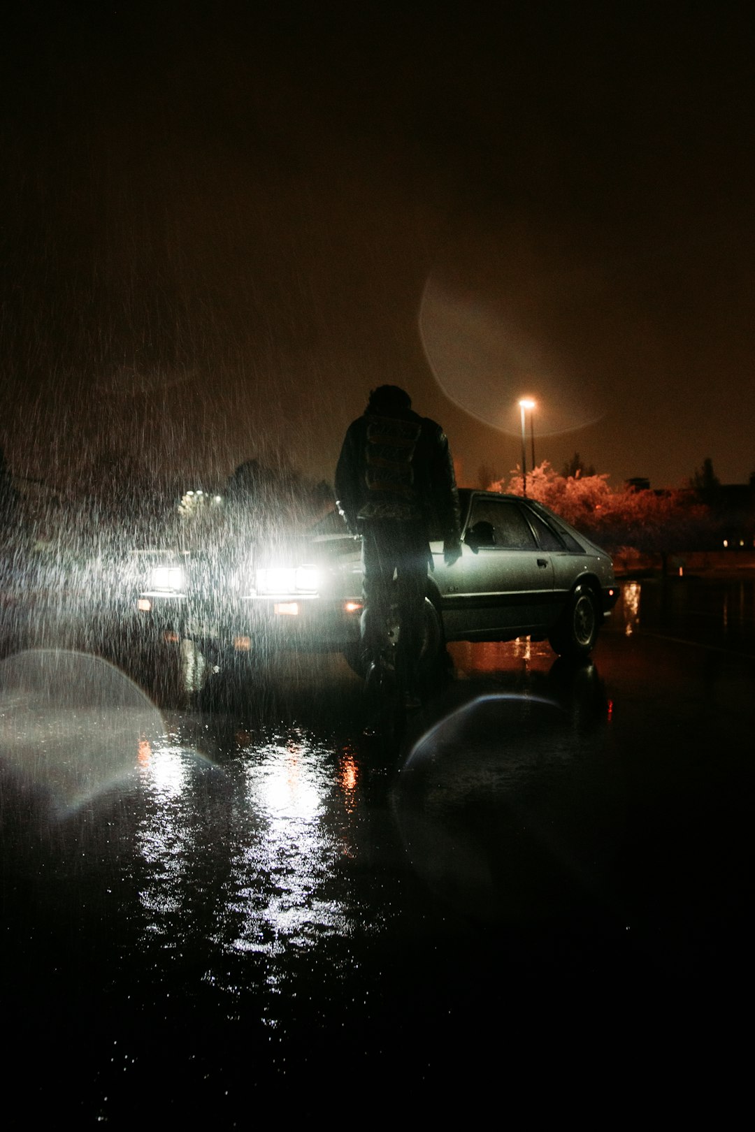 man in black jacket standing near black suv during night time