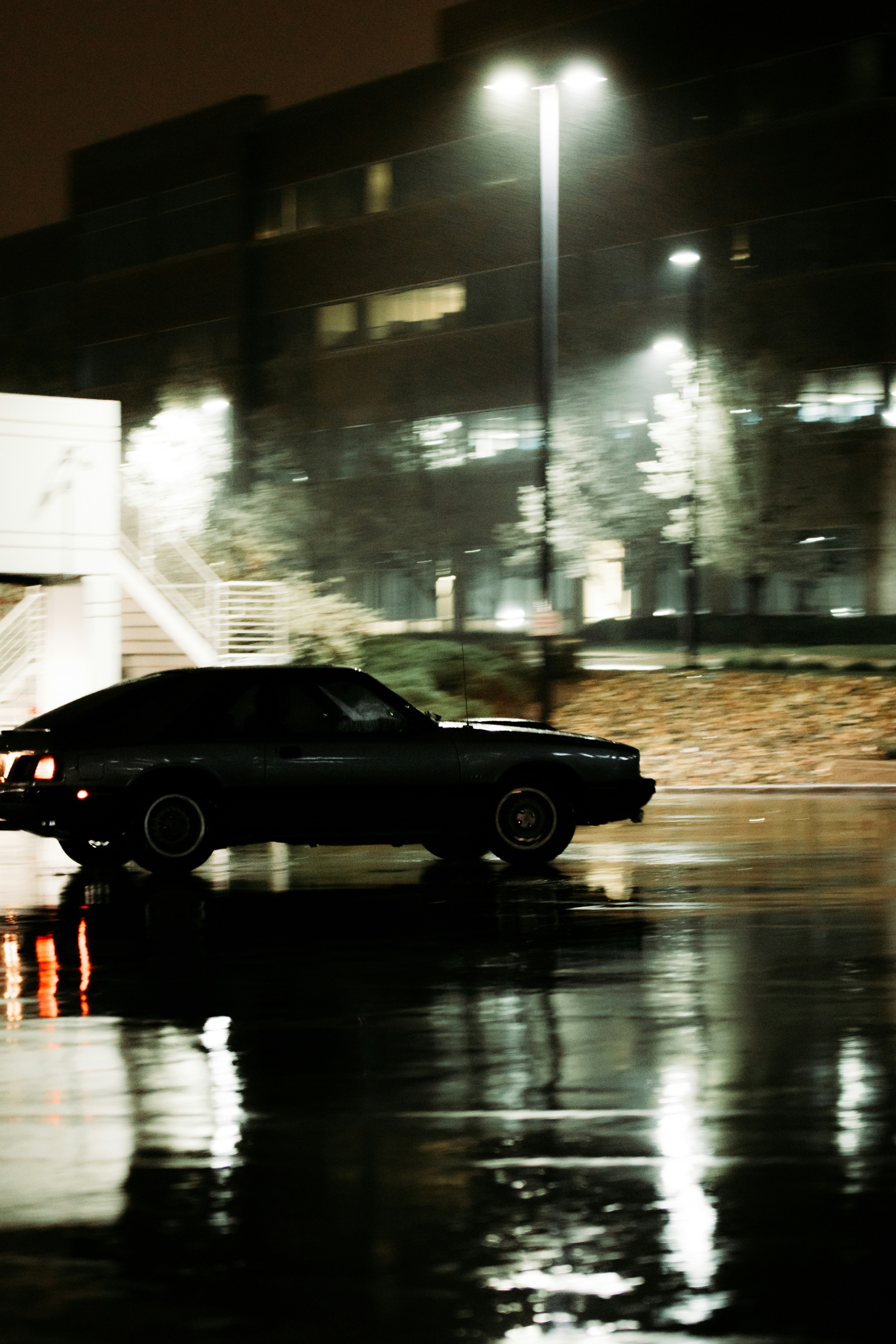 Flat tyre on a car on a dark rainy road, dim streetlights reflecting on wet asphalt