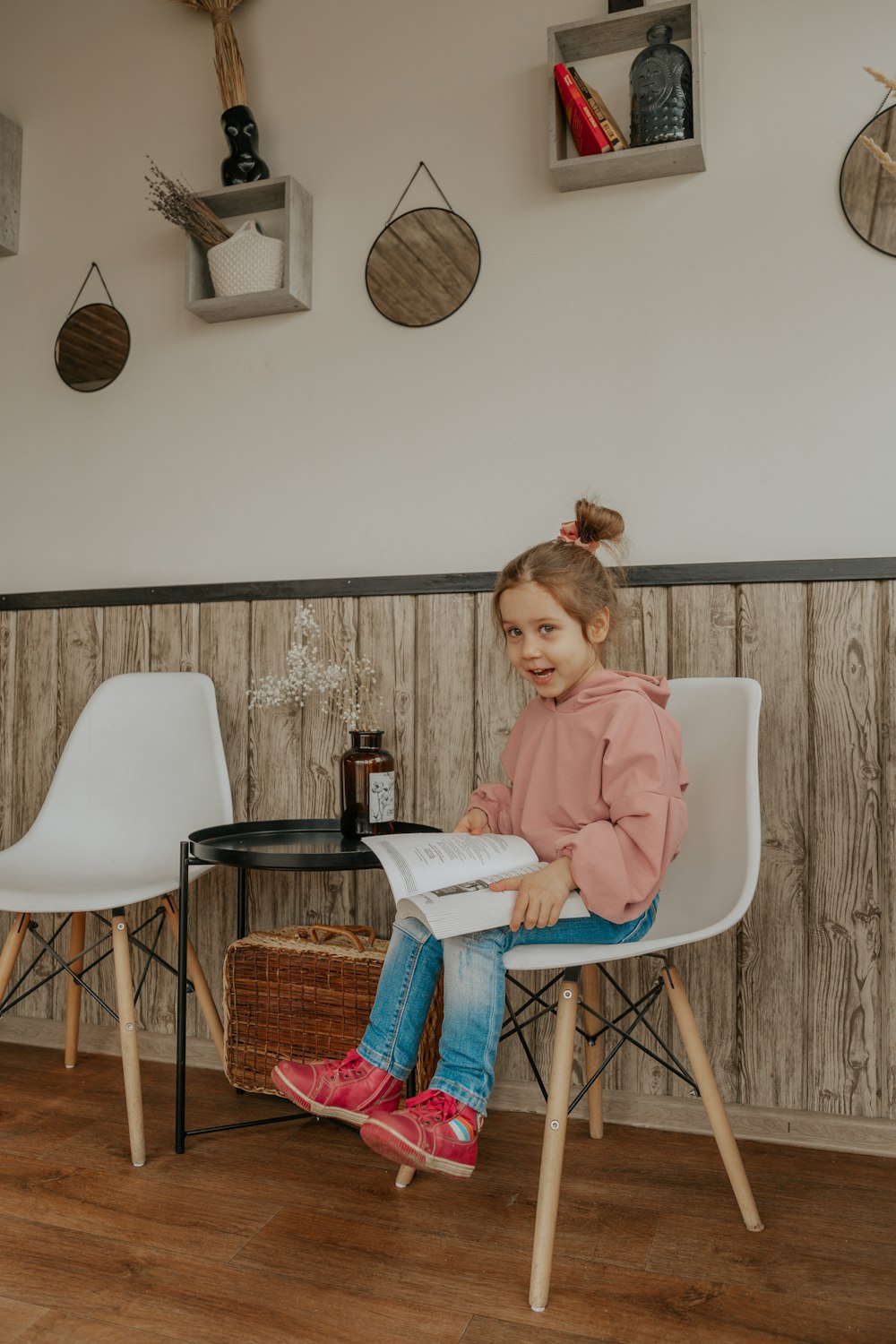 girl in pink long sleeve shirt sitting on white chair reading book