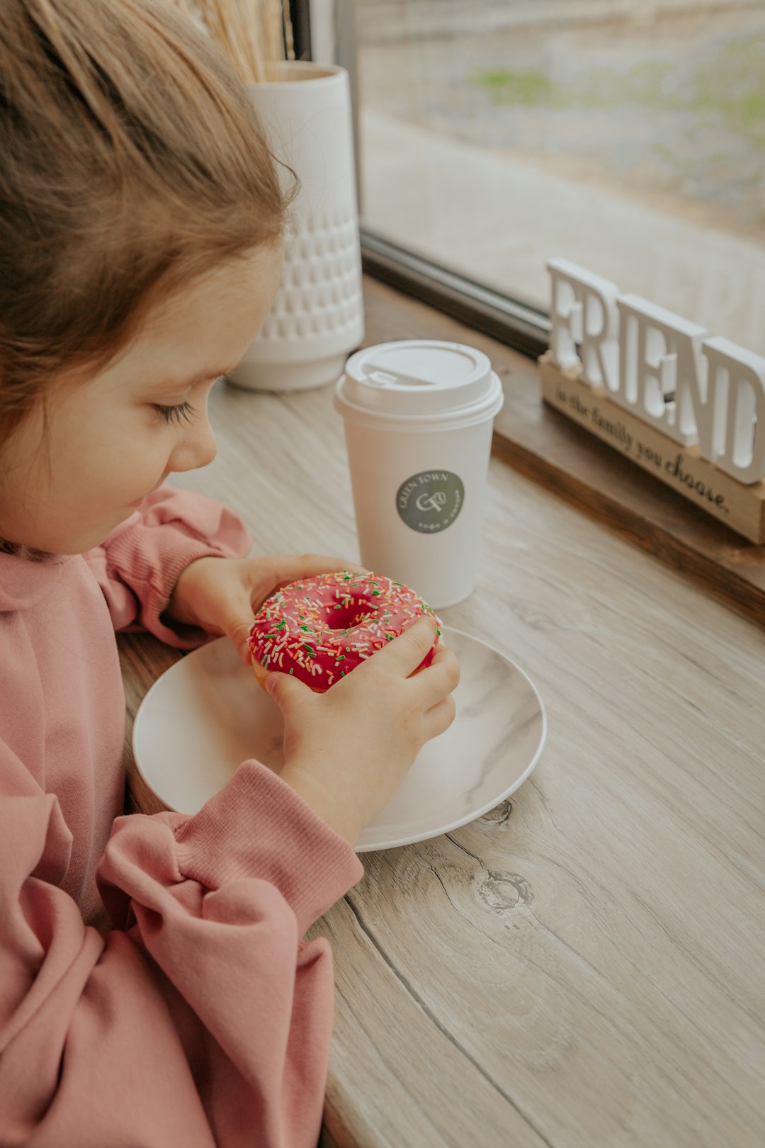 girl in pink dress eating strawberry cake