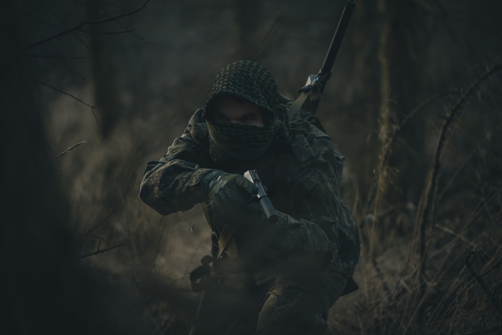 Persona con sudadera con capucha en blanco y negro sosteniendo un rifle