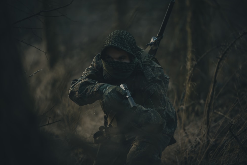 pessoa em preto e branco hoodie segurando rifle