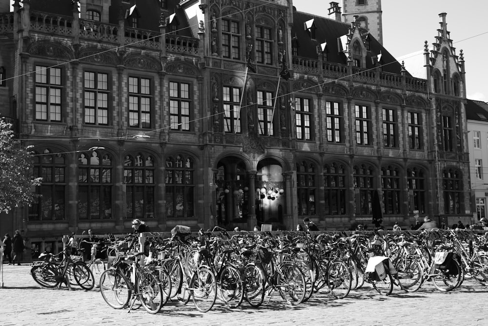 Photo en niveaux de gris de vélos garés près d’un immeuble