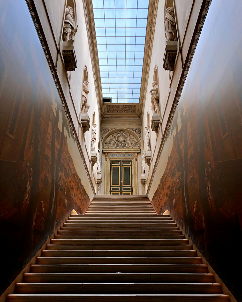 brown wooden staircase in between white concrete building